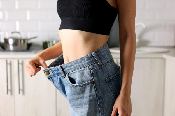 Showcasing an inspiring and triumphant weight loss story with a person joyfully celebrating fitting into loose jeans