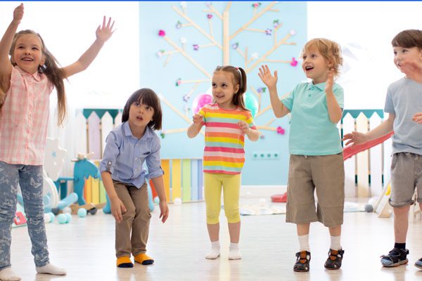 Cheerful kids stand semicircle on floor in kindergarten or day care centre. Preschoolers have fun indoors, playing games Cheerful kids stand semicircle on floor in kindergarten or daycare centre. Preschoolers have fun indoors, playing games